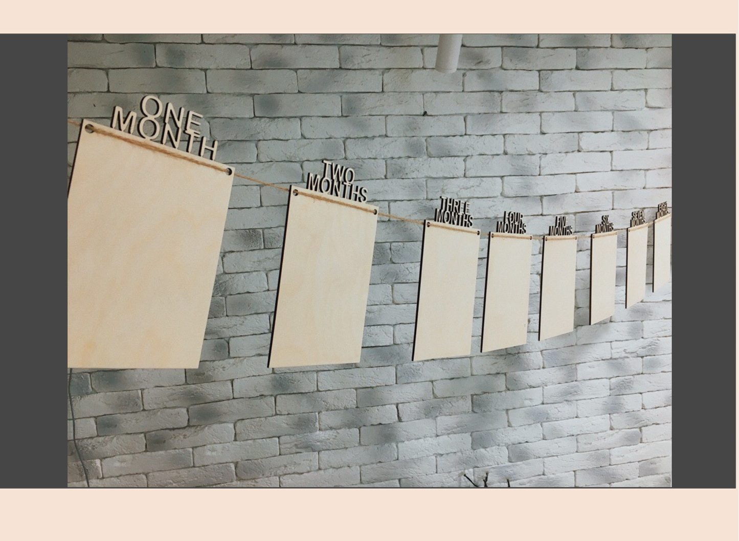 Wooden milestone markers on a brick wall, labeled 'One Month' to 'Nine Months'.