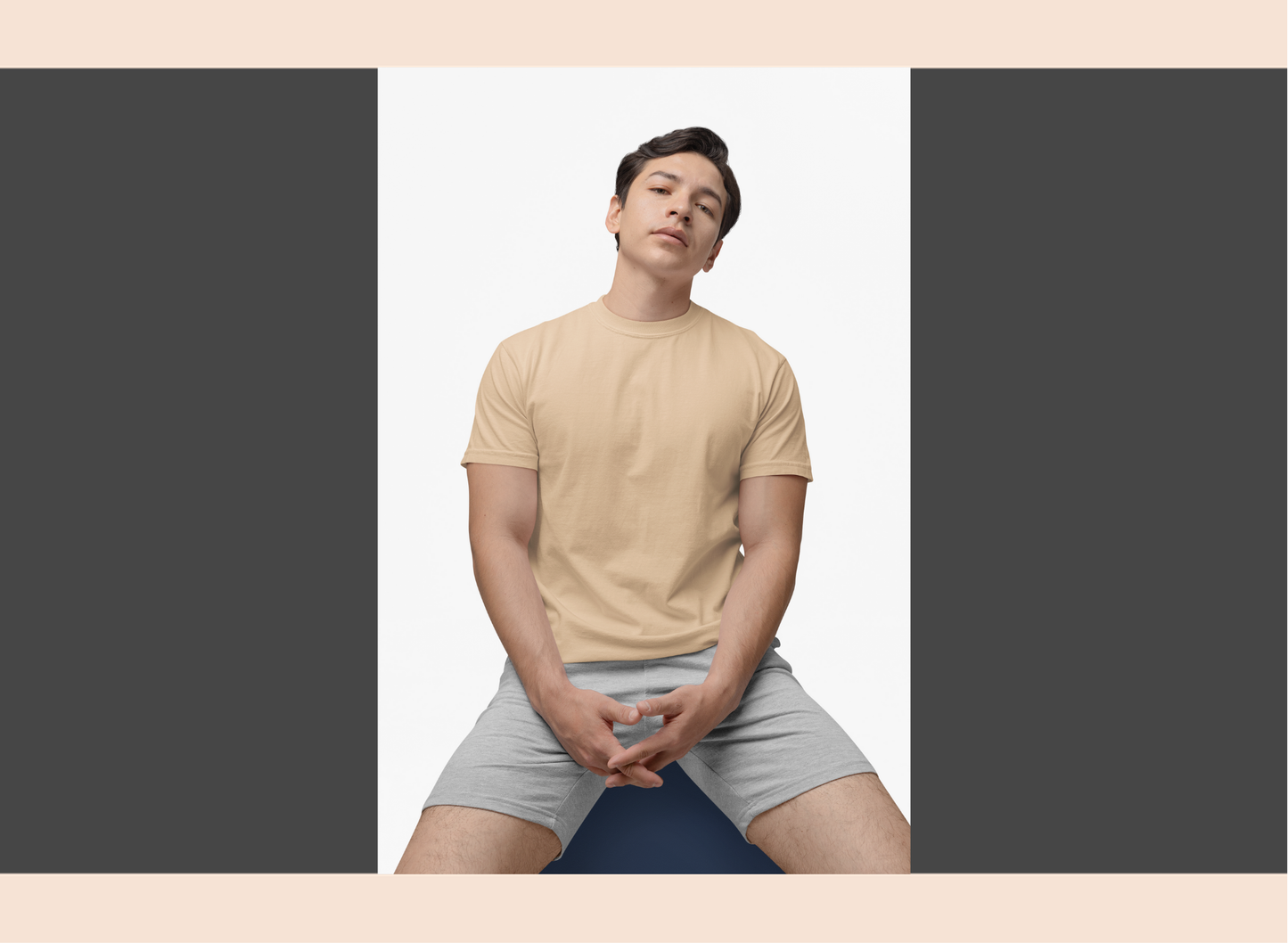 Person wearing a beige t-shirt and gray shorts sitting on a blue yoga mat against a white background