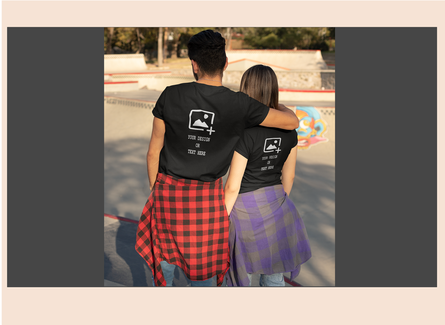 Two people wearing matching black t-shirts with a graphic design at a skate park.