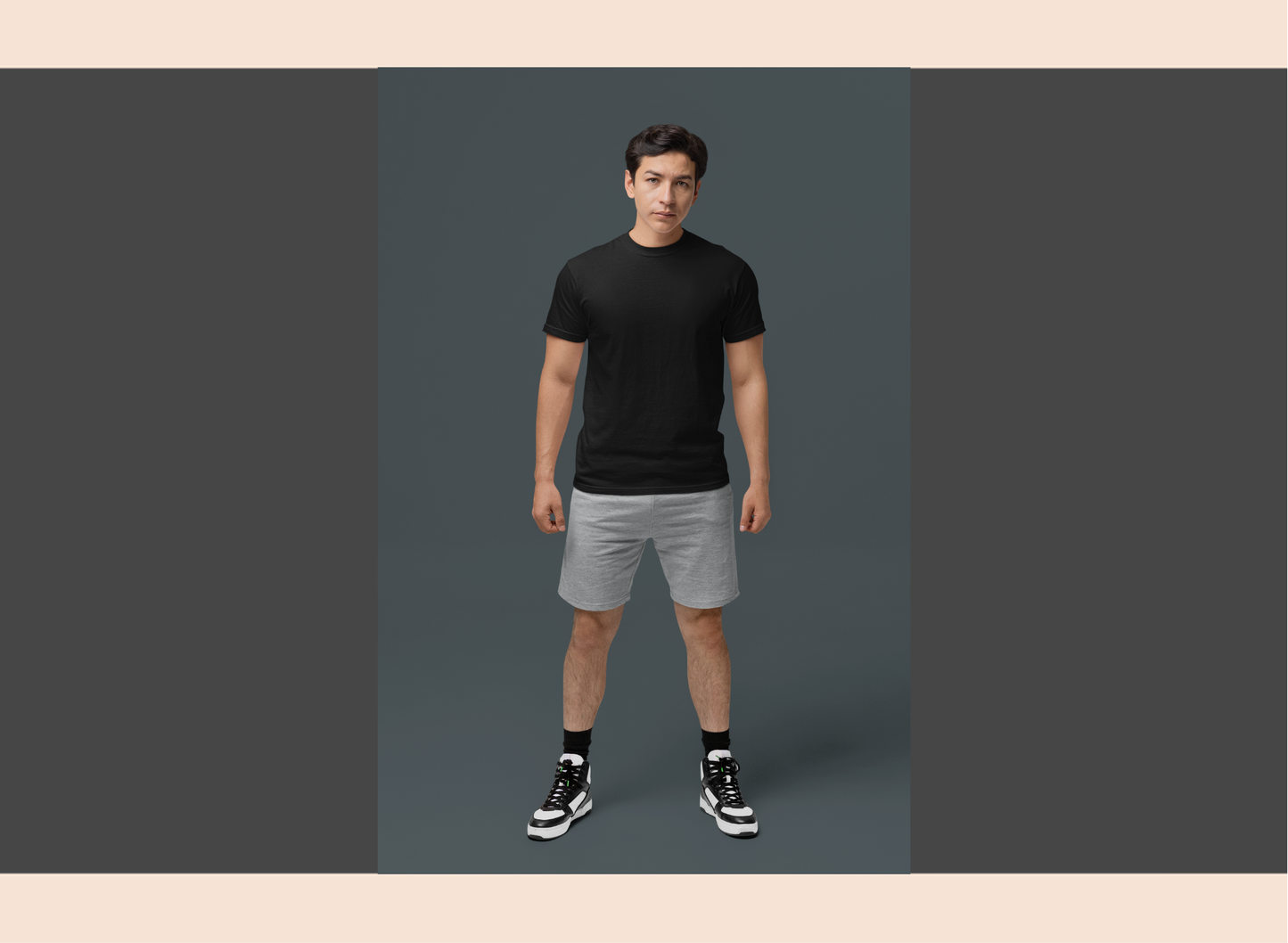 Man wearing a black t-shirt and gray shorts on a gray background