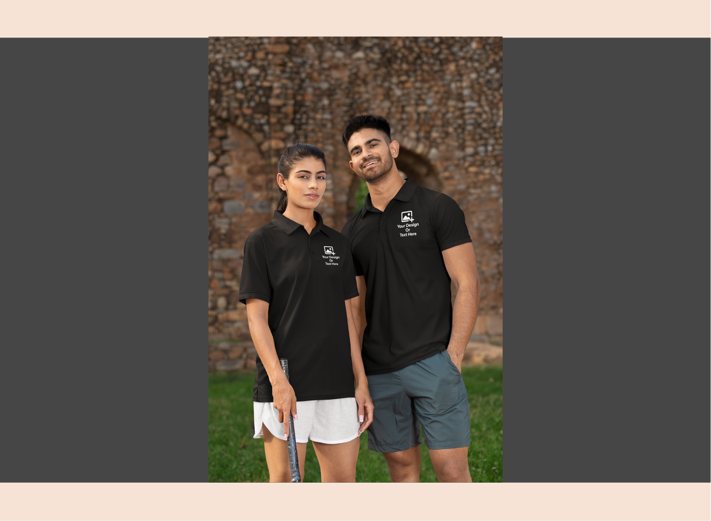 Two people wearing black polo shirts standing outdoors with a brick wall background