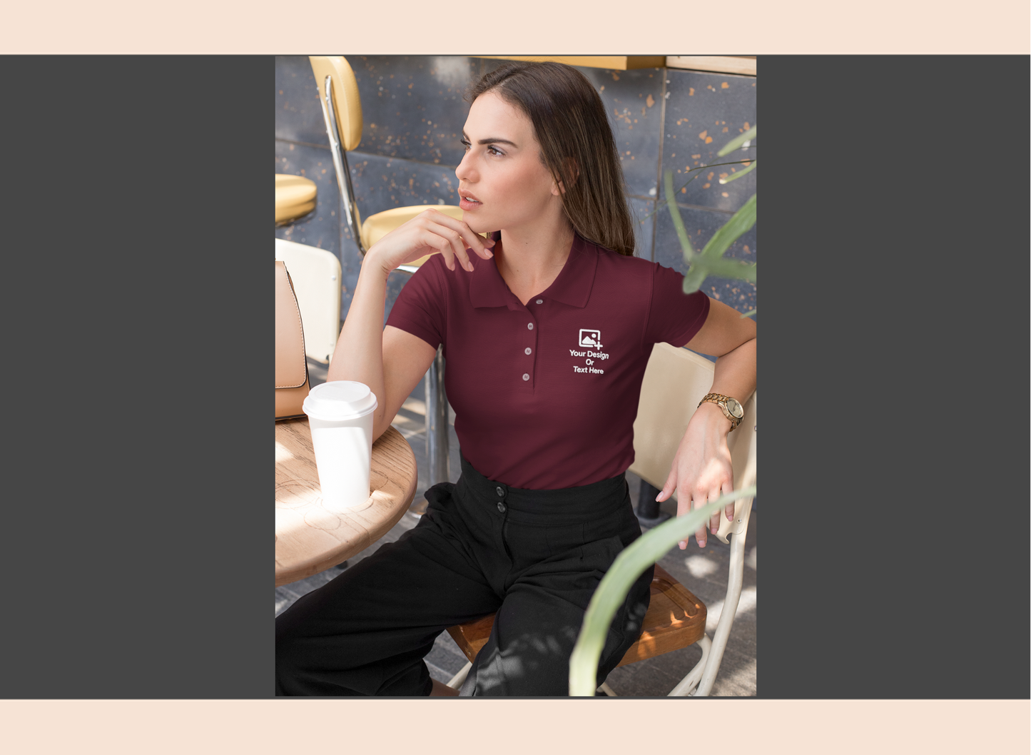 Woman wearing a maroon polo shirt with a logo, sitting at a table in a casual setting.
