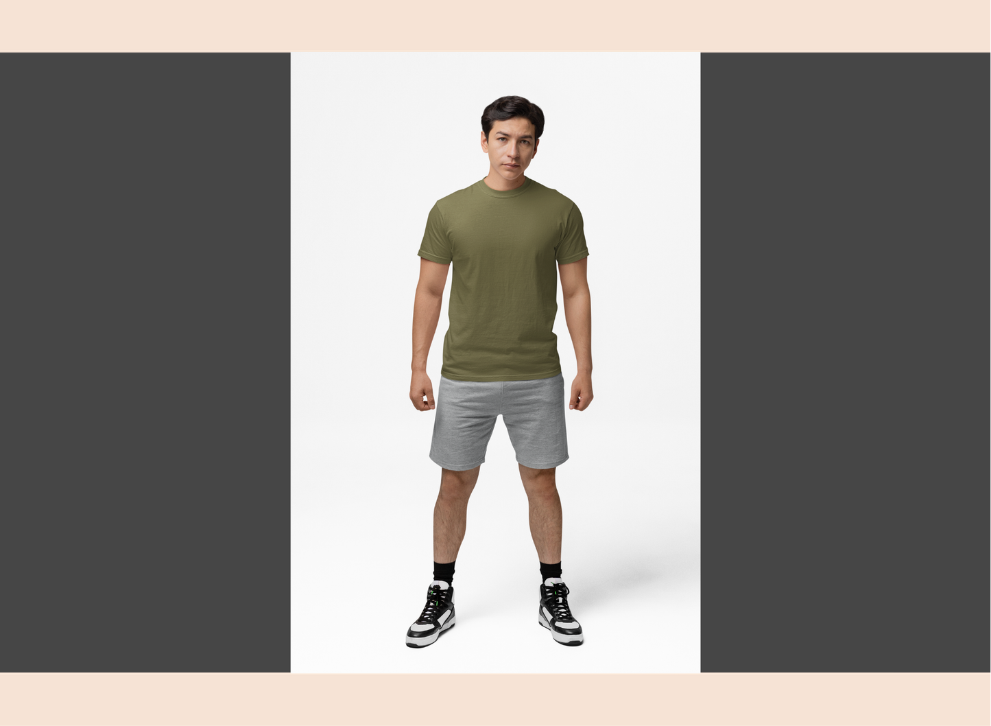 Man wearing a green t-shirt and gray shorts standing against a white background