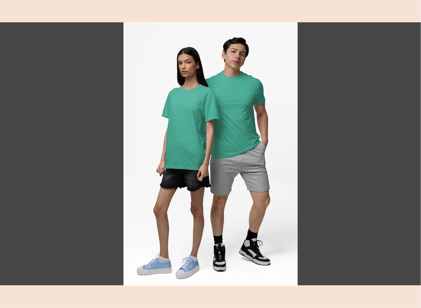 Two people wearing matching green t-shirts and gray shorts on a white background
