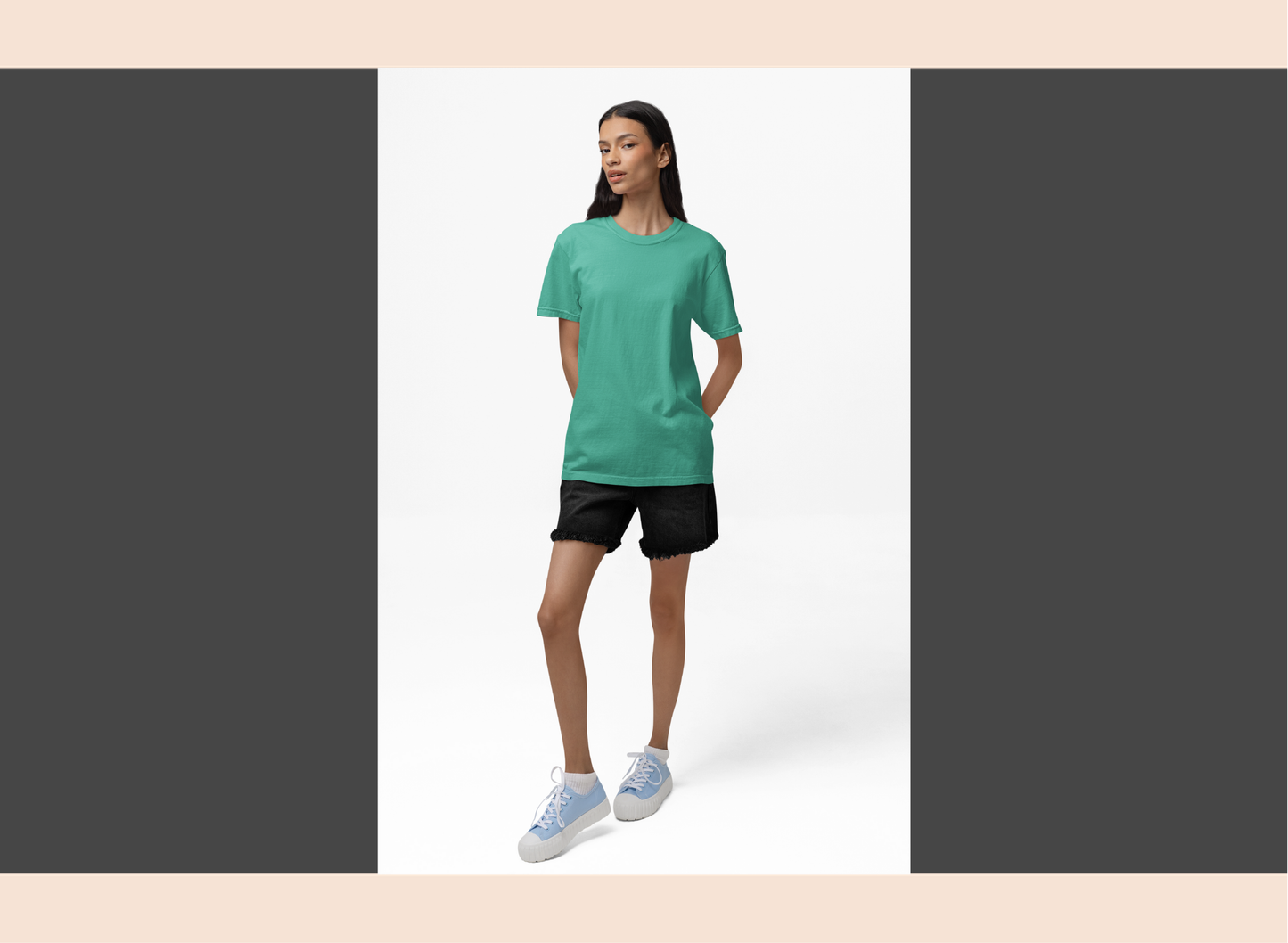 Woman wearing a green t-shirt and black shorts standing against a white background