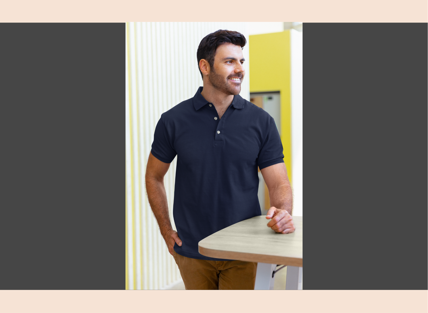 Man wearing a navy blue polo shirt standing in an office setting.
