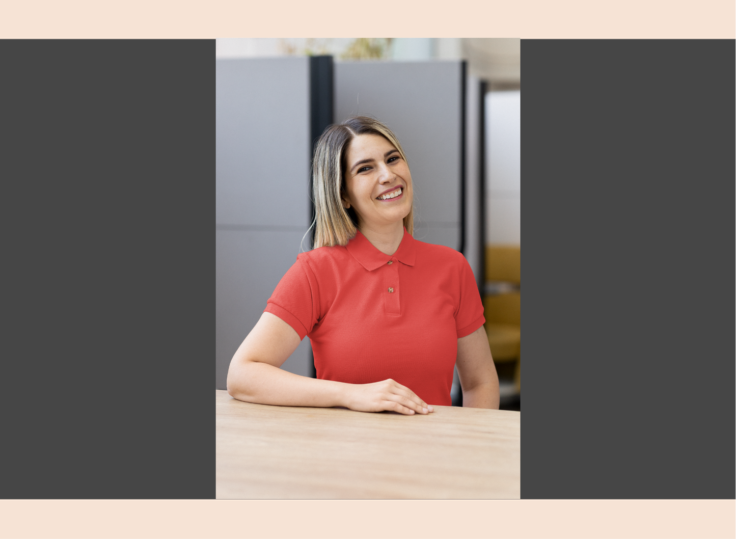 Woman in a navy polo shirt sitting at a desk in an office setting