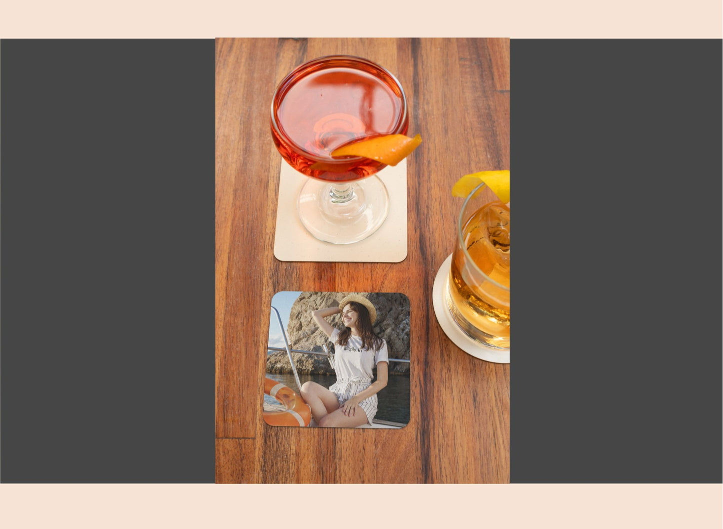Two glasses of cocktails on a wooden table with a coaster featuring a photo of a woman.