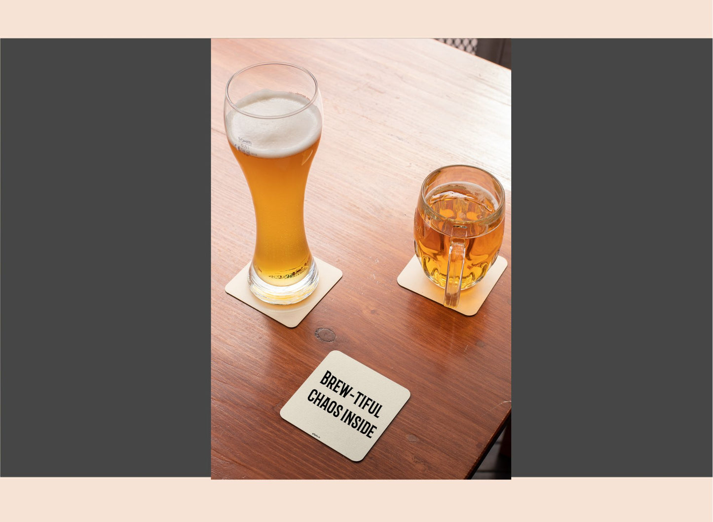 Two glasses of beer on a wooden table with a coaster underneath.
