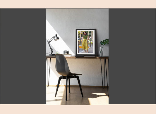Modern office desk with a chair and framed photo on a wall.