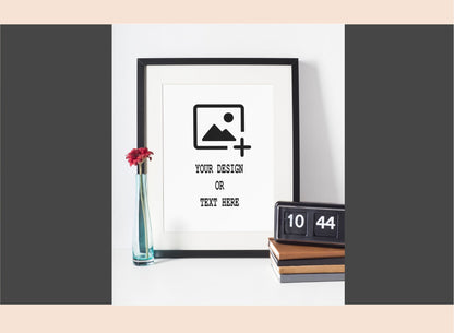 Framed mockup with customizable text and design area, placed on a white surface with decorative items.