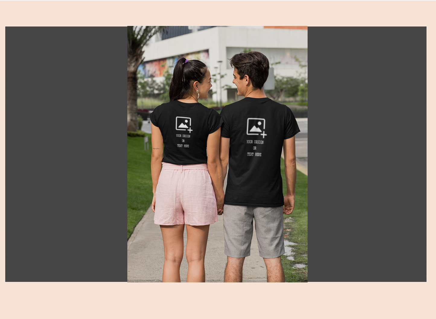 Two people wearing black t-shirts with a logo on the back, standing outdoors.