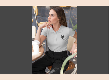 Woman wearing a white polo shirt with a logo, sitting in a cafe.