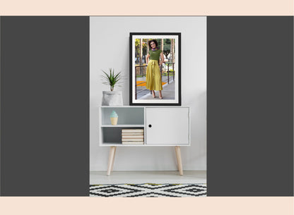 Framed photo of a woman on a wall above a white cabinet with books and decor items.