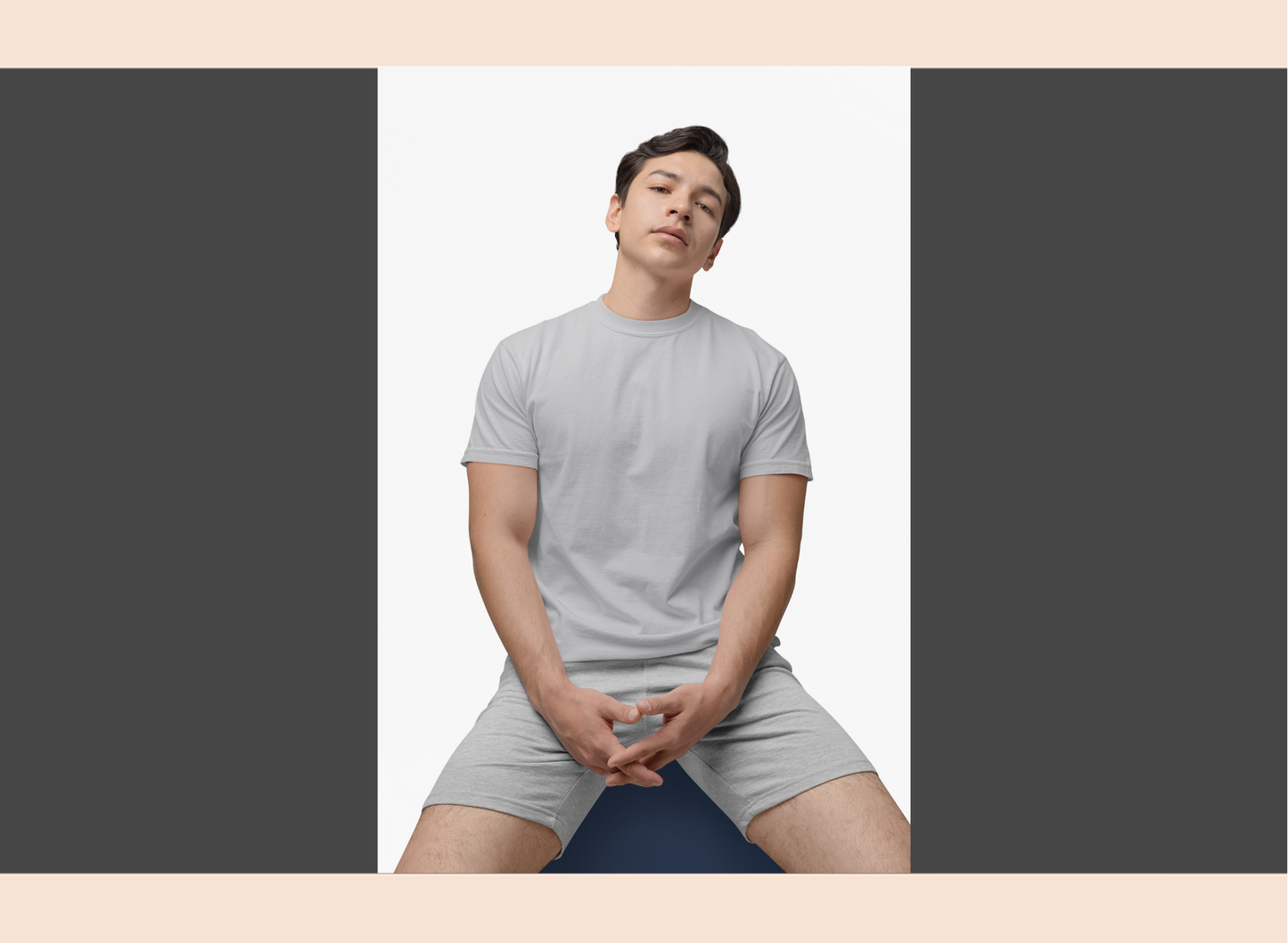 Person wearing a gray t-shirt and shorts sitting on a blue yoga mat against a plain background