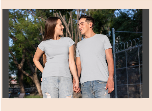 Two people standing outdoors holding hands, wearing matching gray t-shirts and jeans.
