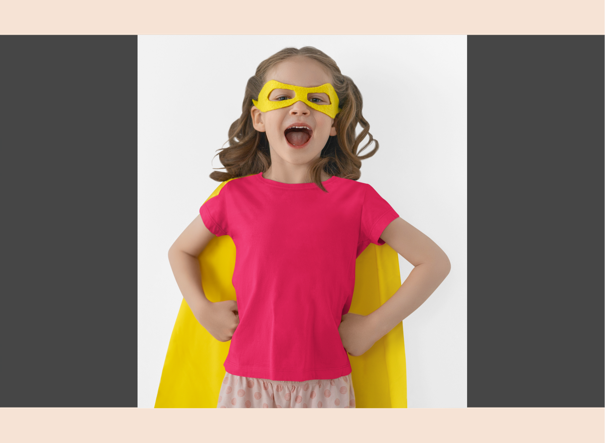 Child wearing a pink shirt, yellow cape, and mask on a white background