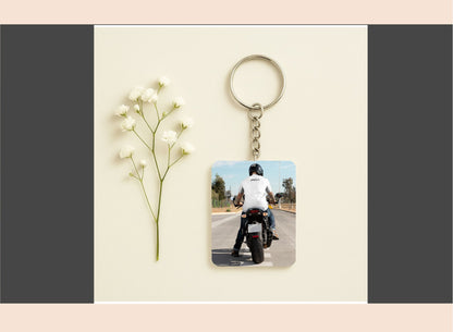 Keychain with photo of person on a motorcycle next to a small plant on a beige background