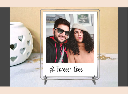 Polaroid frame with a photo of a couple and '#Forever Love' text on a decorative surface.
