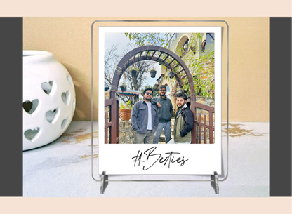 Acrylic polaroid frame with a photo of three people and 'Besties' text on a decorative surface.