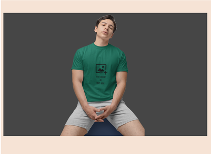 Person wearing a green t-shirt with a graphic design on a dark background