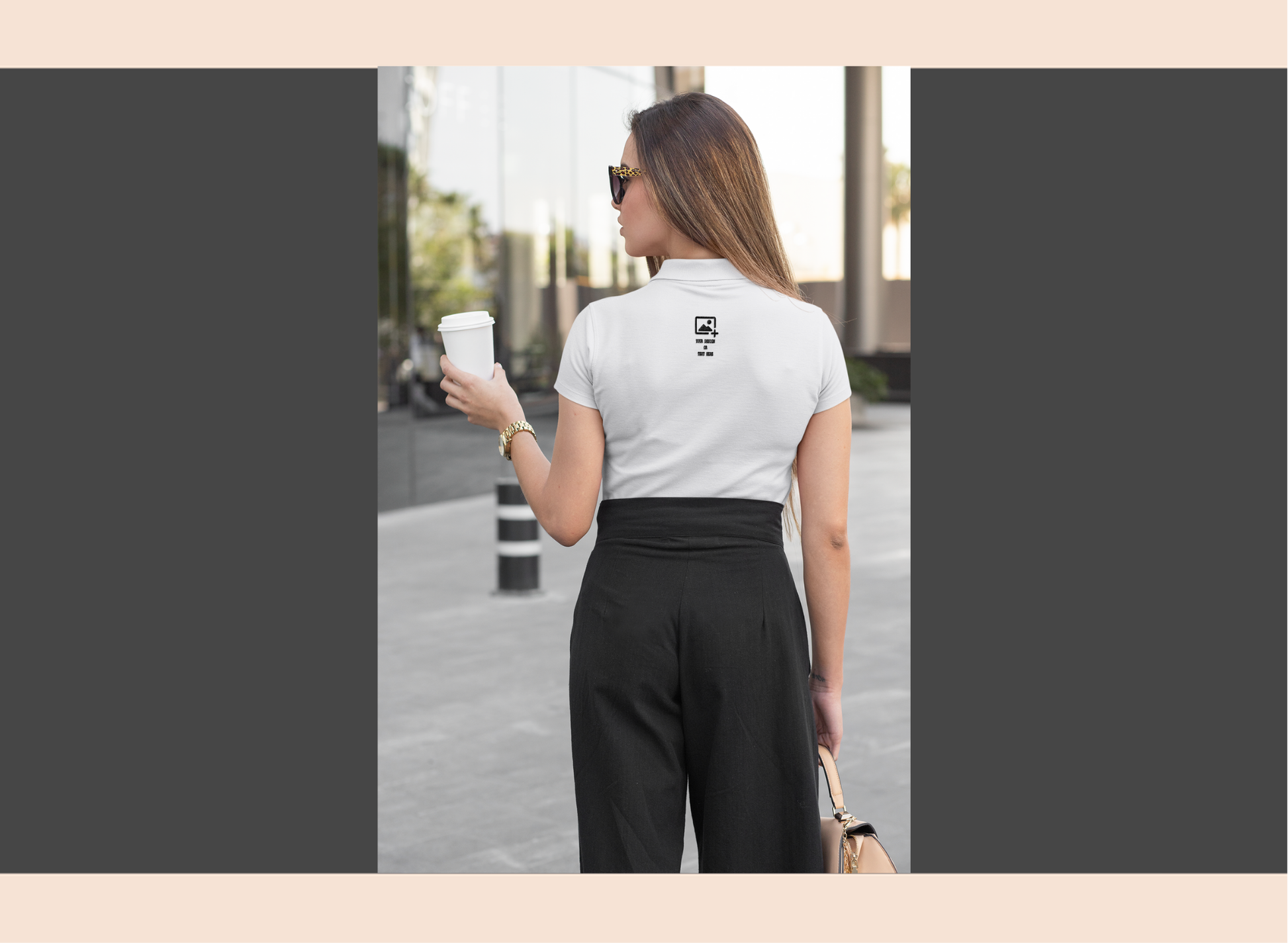 Woman wearing a blue t-shirt with a logo and text, holding a coffee cup on a city street.