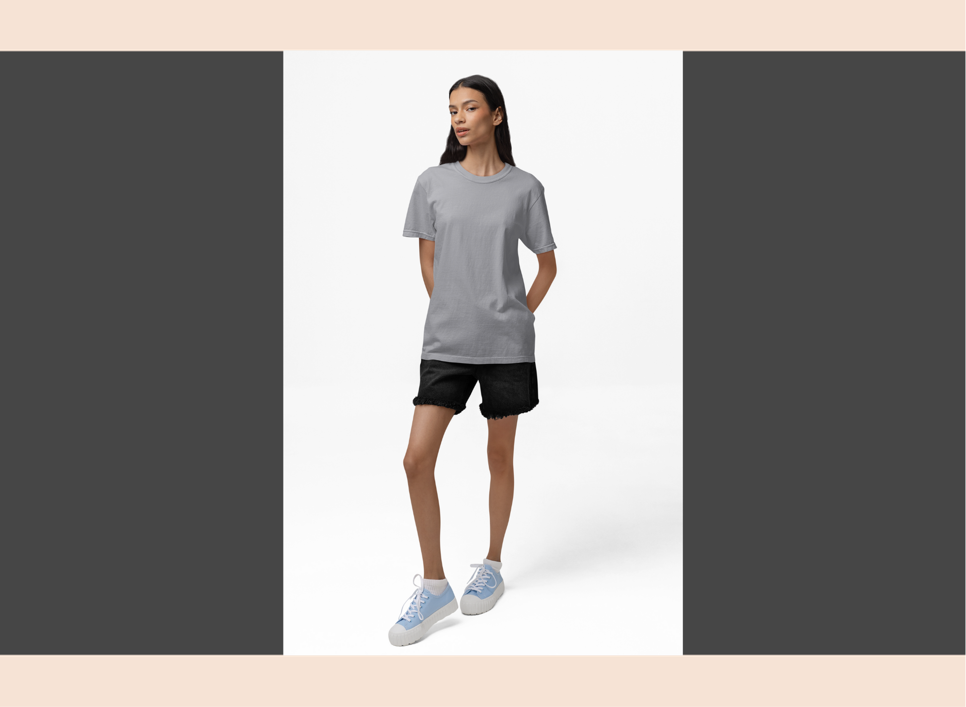 Woman wearing a gray t-shirt and black shorts standing against a white background
