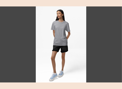Woman wearing a gray t-shirt and black shorts standing against a white background