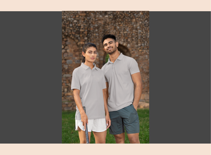 Two people wearing matching gray polo shirts and shorts standing outdoors.