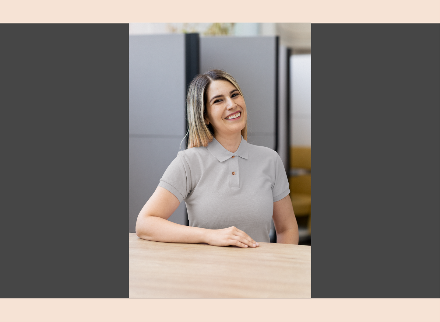 Woman in a gray polo shirt sitting at a desk in an office setting