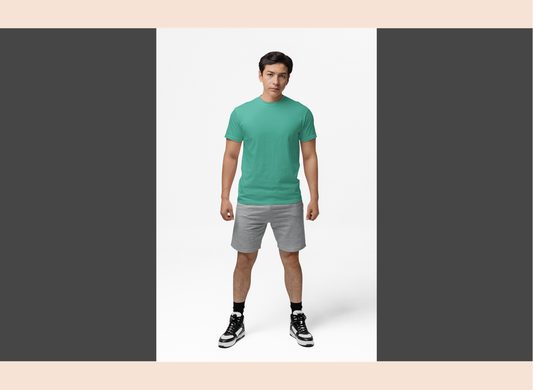 Man wearing a green t-shirt and gray shorts standing against a white background