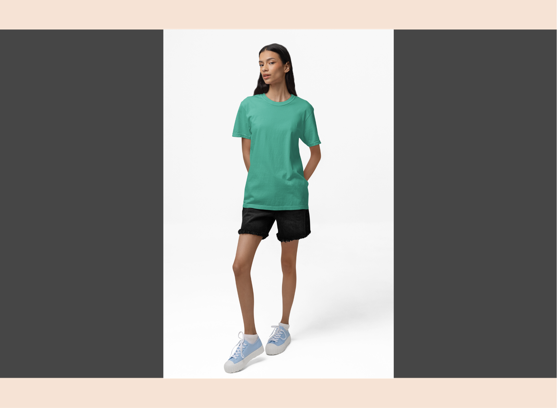 Woman wearing a green t-shirt and black shorts standing against a white background