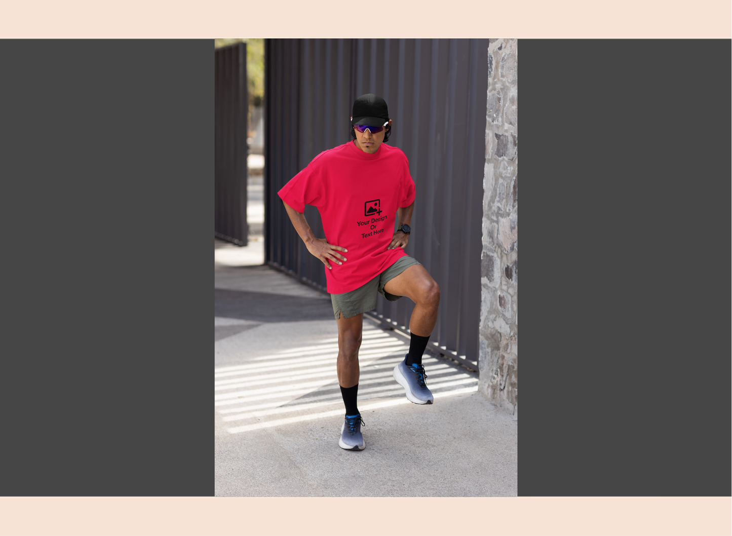 Person wearing a red t-shirt and gray shorts standing outdoors near a stone wall.