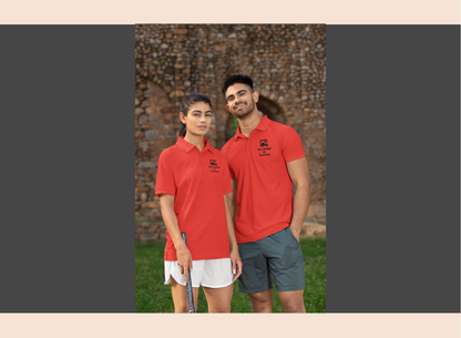 Two people wearing navy polo shirts with a logo, standing outdoors against a brick wall.
