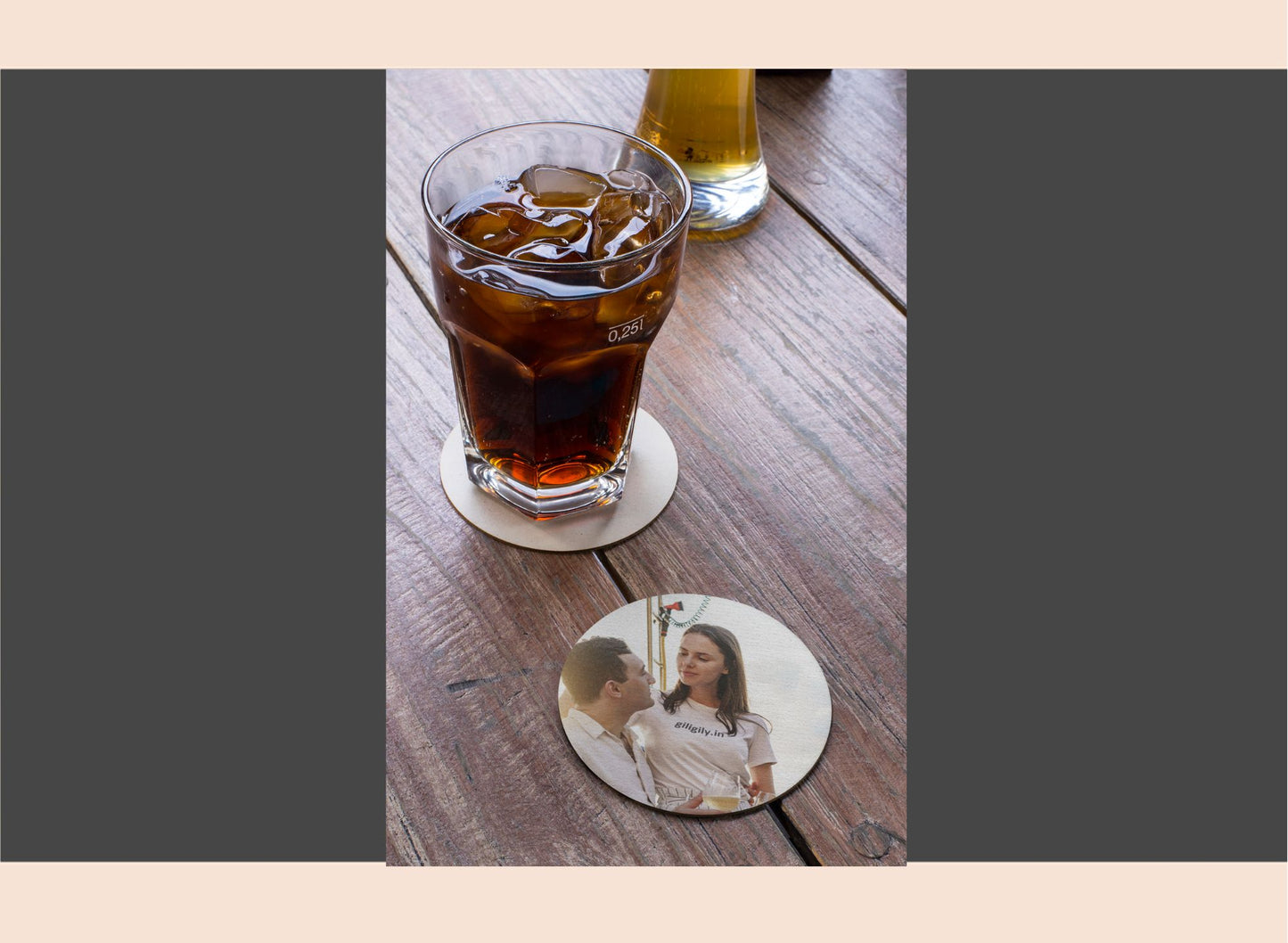 Glass of iced tea on a wooden table with a coaster featuring a couple's photo.