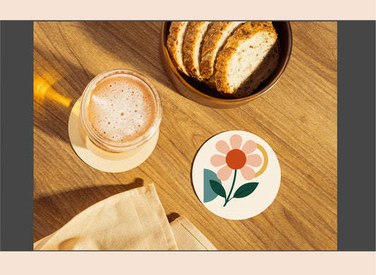 Glass of a beverage, bowl of bread, and floral coaster on a wooden surface