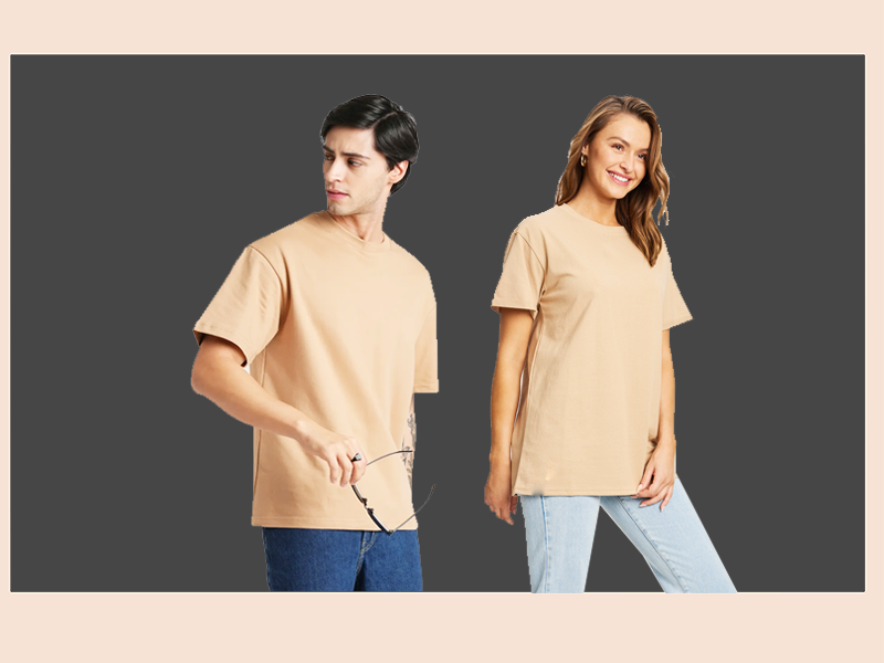 A male and a female model wearing plain beige round drop shoulder t-shirts with a relaxed fit.
