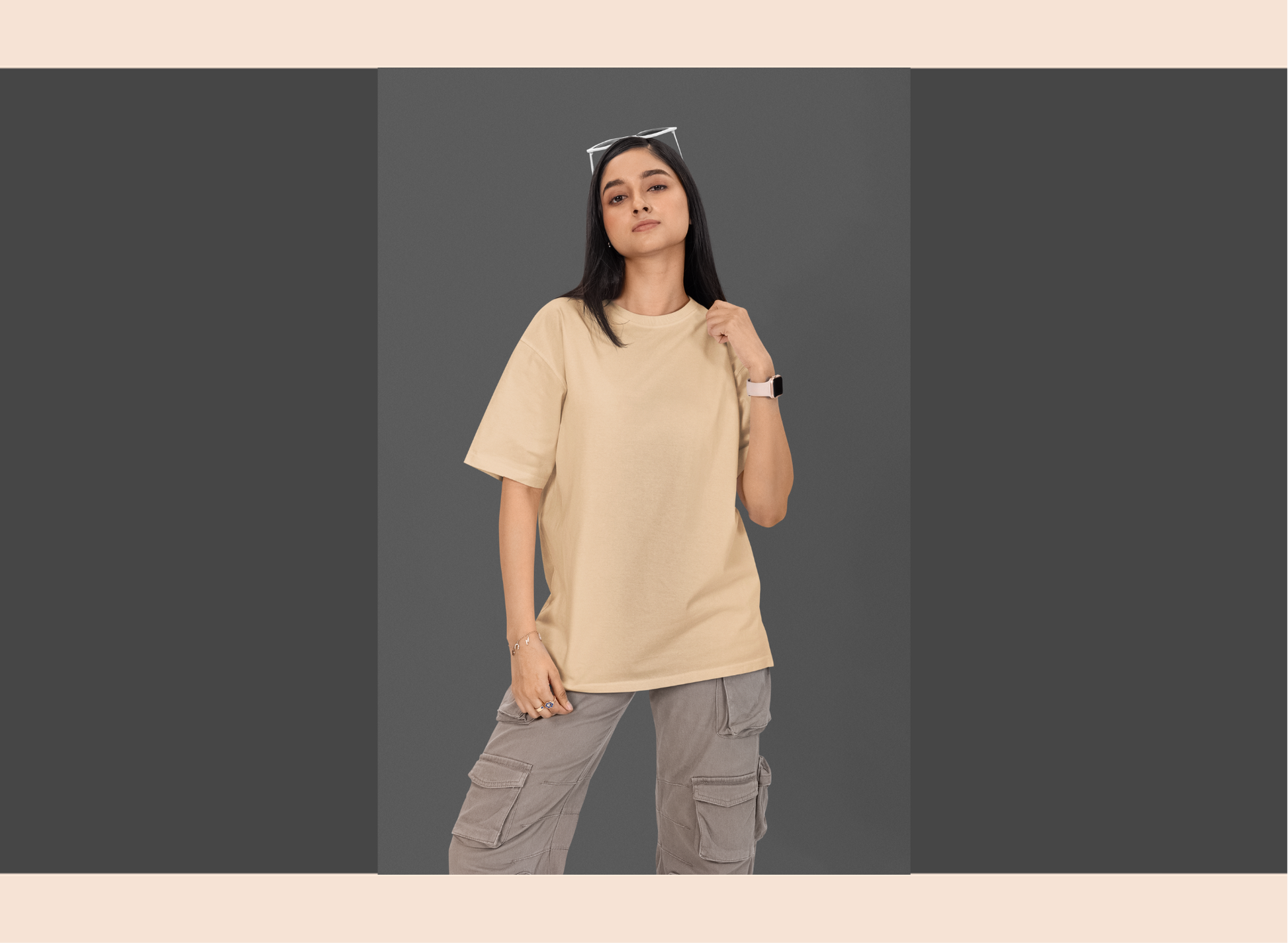 Person wearing a beige oversized t-shirt and gray cargo pants on a plain background