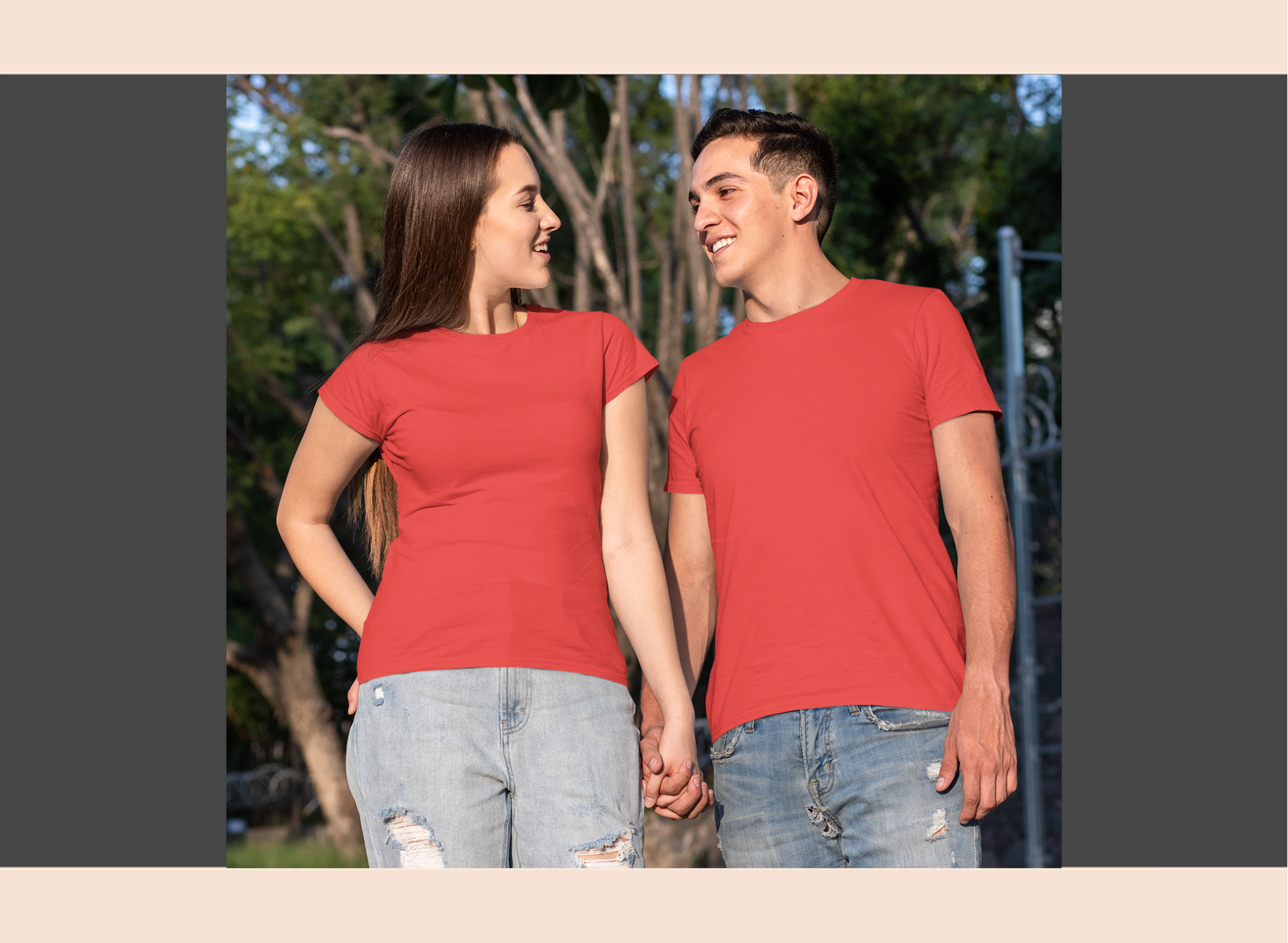Two people wearing red t-shirts standing outdoors with trees in the background