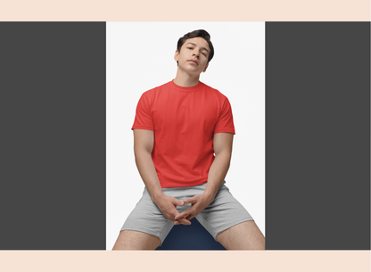 Person wearing a red shirt and gray shorts sitting on a blue yoga ball against a white background