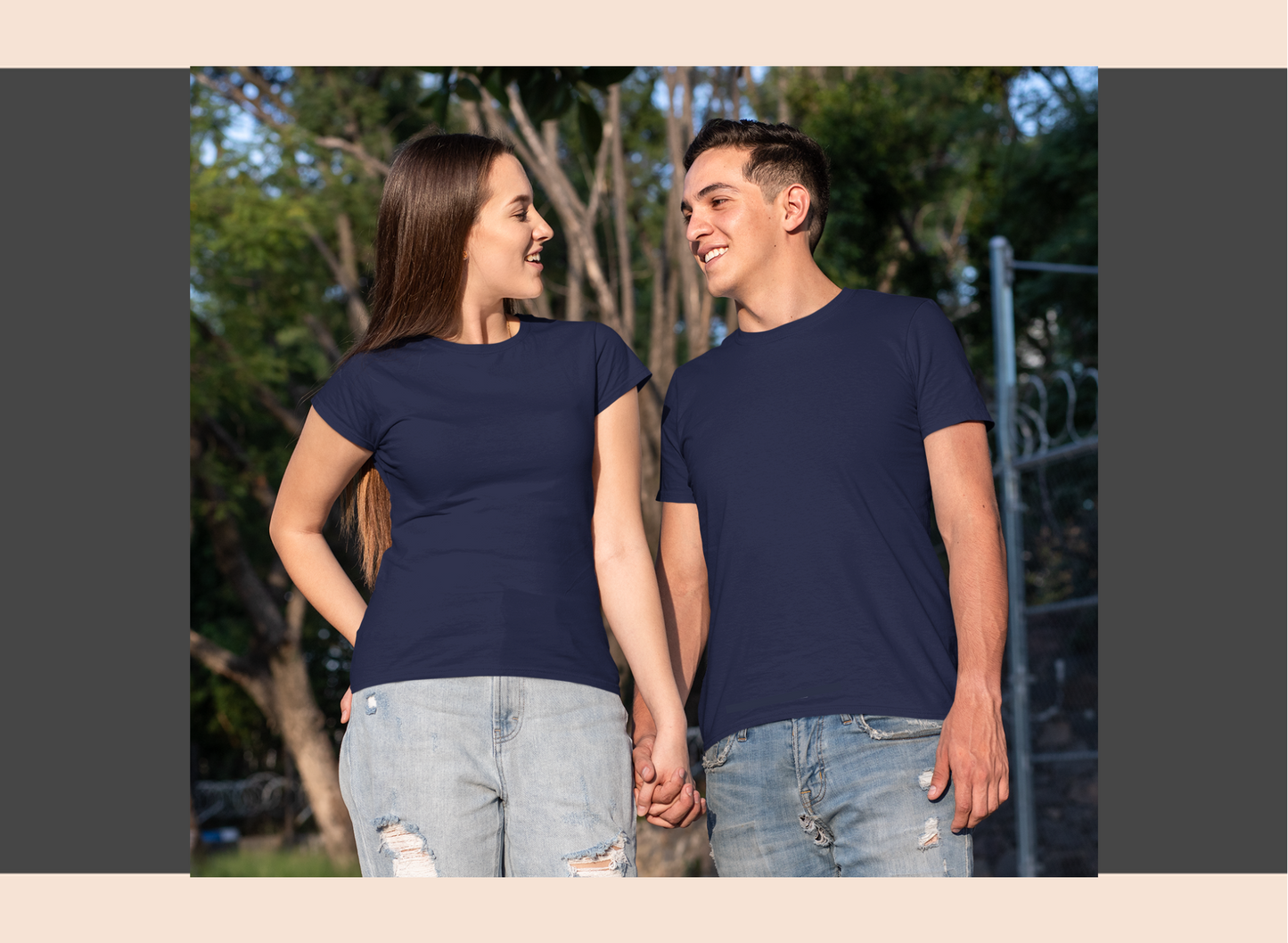Two people wearing navy blue t-shirts standing outdoors with trees in the background