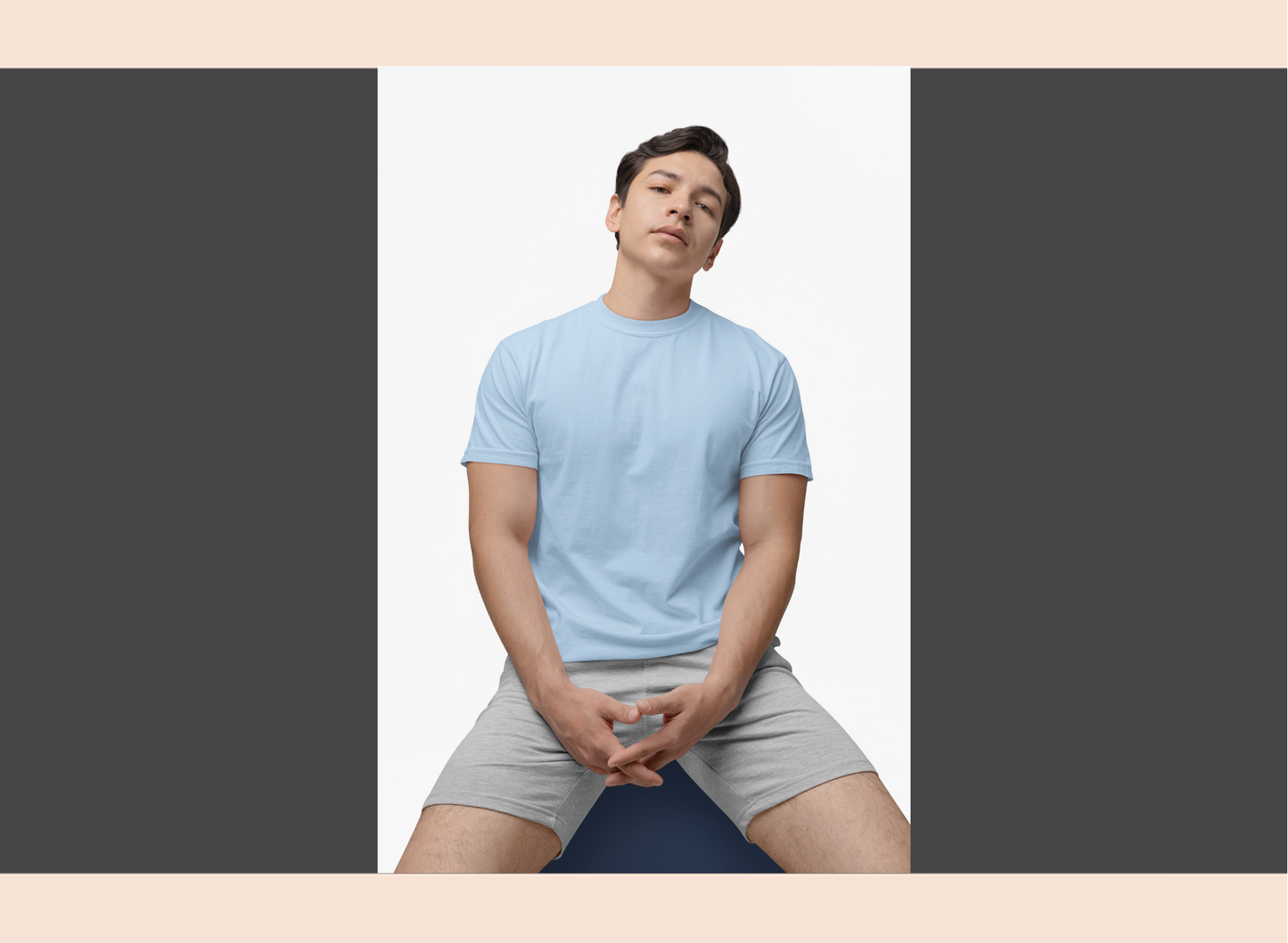 Person wearing a light blue t-shirt and gray shorts sitting on a yoga mat.