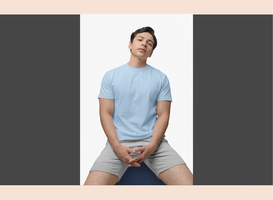 Person wearing a light blue t-shirt and gray shorts sitting on a yoga mat.