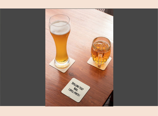 Two glasses of beer on a wooden table with a coaster underneath.