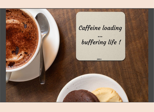 Cup of coffee with a dessert on a wooden table, coaster with text 'Caffeine loading... buffering life!'