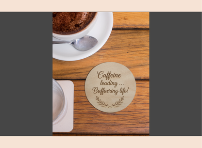 Wooden coaster with humorous text on a wooden table with a cup of coffee.