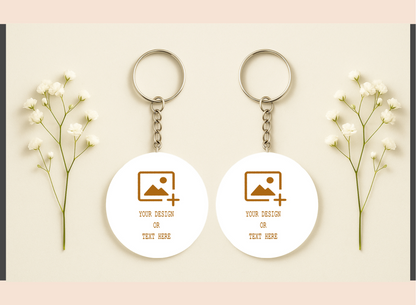 Two white keychains with customizable design or text on a light pink background with baby's breath flowers.
