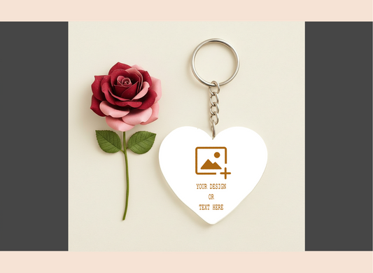 Heart-shaped keychain with customizable design area next to a red rose on a light background